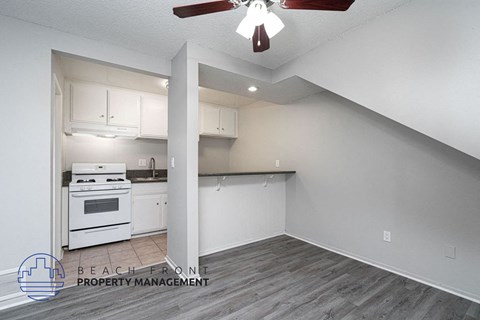 a kitchen with white cabinets and a stove and a ceiling fan